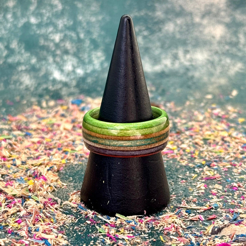 Green, purple and teal recycled skateboard wood ring displayed on a black ring cone, showing layered maple and wood grain.