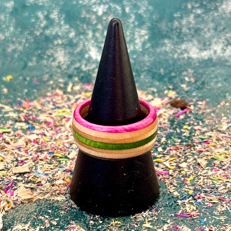 Pink, green and black skateboard maple ring on a black ring holder cone.
