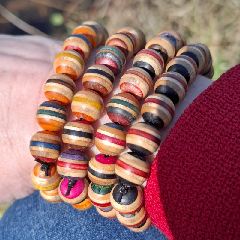 Assorted Colour Skateboard Bracelet made of round wooden beads with multicoloured stripes on a wrist outdoors