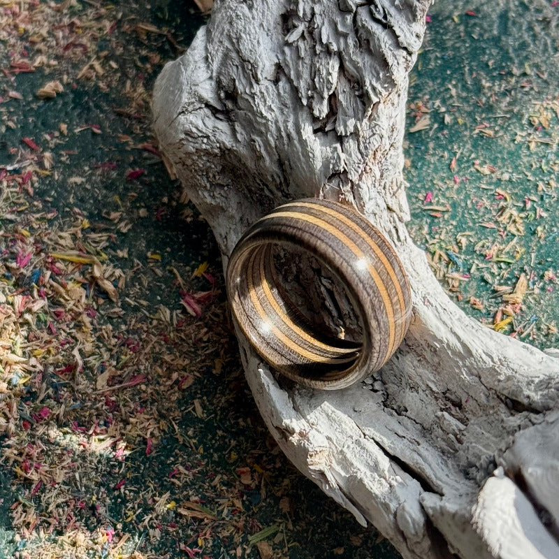 Dark grey skateboard maple ring on a textured wood surface, its layers catching the light.