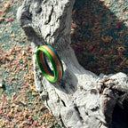 Slim skateboard maple ring with green and blue outer bands, on driftwood.