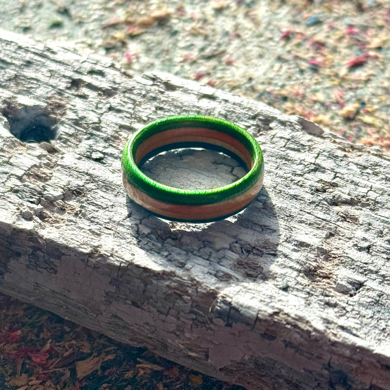 Slim green and blue skateboard maple ring on a textured surface, handmade by Baltic Dew.