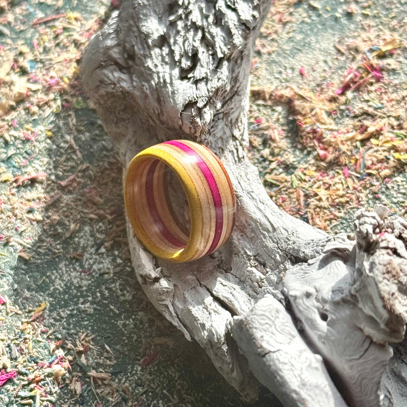 Yellow and pink skateboard maple ring resting on a textured wood surface.