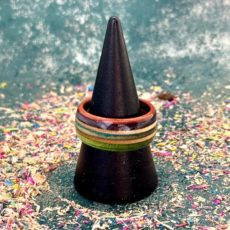 Green, purple and teal recycled skateboard wood ring shown with a second layered skateboard ring on a black ring cone.