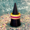 Yellow and pink skateboard maple ring on a black ring holder, stripes running around the band.