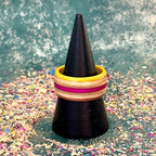 Yellow and pink skateboard maple ring on a black ring holder, stripes running around the band.