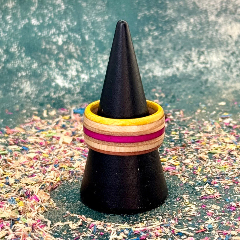 Yellow and pink skateboard maple ring on a black ring holder, stripes running around the band.