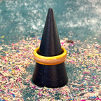 Slim yellow and orange skateboard maple ring on a black cone, with wood shavings behind.